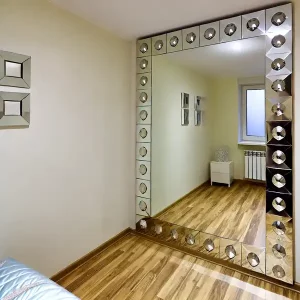 A small room featuring a large mirror on the wall and reflective decor